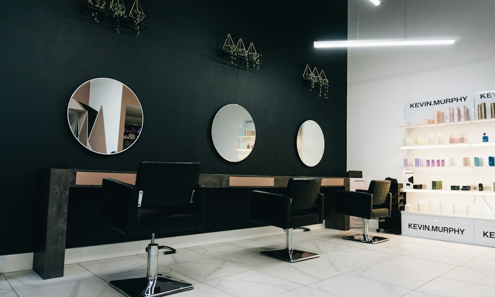 Yuvarlak aynaları ve ferah bakım alanları olan modern bir güzellik salonu